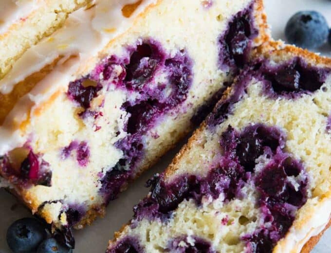 Blueberry Lemon Pound Cake! This pound cake is made lighter by using greek yogurt, and is loaded up with lemon flavor thanks to zest and fresh lemon juice! Juicy blueberries are baked right in. All drizzled with a luscious lemon glaze.