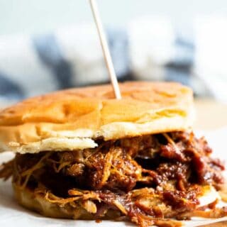 Slow cooker pulled pork mixed with a Texas style BBQ sauce on a bun making a pulled pork sandwich.