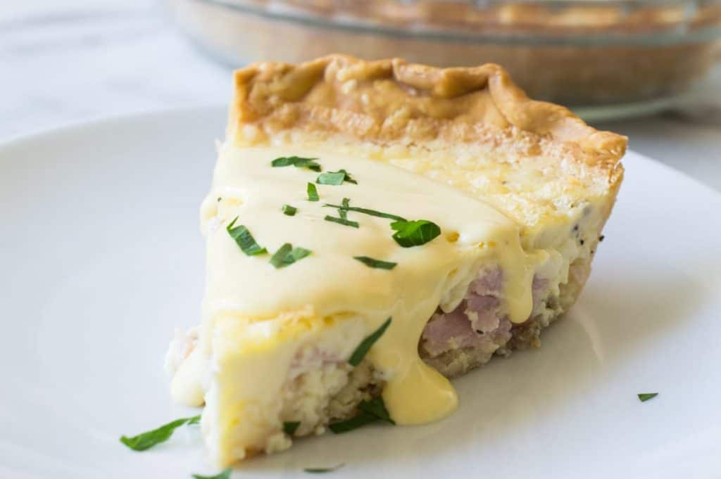 Eggs Benedict Quiche! This super easy to make quiche comes out with perfectly flakey crust, creamy egg and bites of canadian bacon. Not to mention it's smothered in an easy to make blender hollandaise sauce. Perfect for brunch and upcoming Mother's Day! 