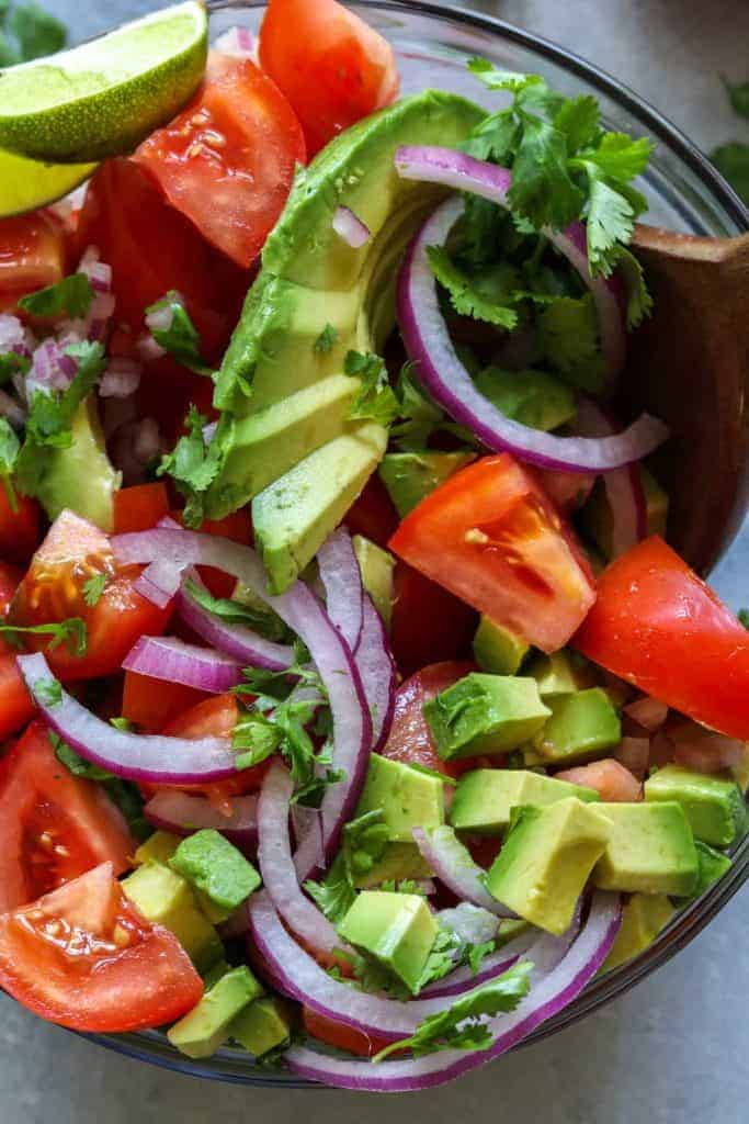 Avocado Tomato Cilantro Salad!  Refreshing and bursting with flavor this salad will be the perfect complement to any meal this summer!  Fresh tomato, avocado, cilantro all swimming in a lime dressing.  Plus top it with some crumbled queso fresco for a bit of creaminess.  