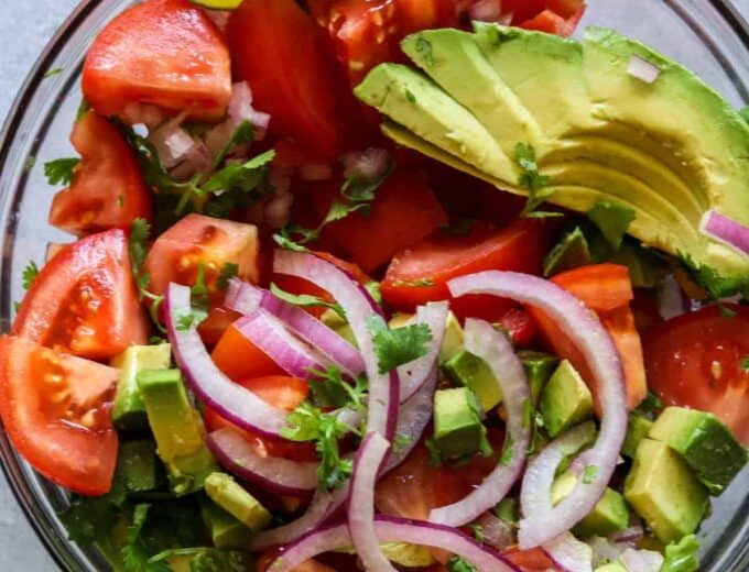 Avocado Tomato Cilantro Salad!  Refreshing and bursting with flavor this salad will be the perfect complement to any meal this summer!  Fresh tomato, avocado, cilantro all swimming in a lime dressing.  Plus top it with some crumbled queso fresco for a bit of creaminess.  