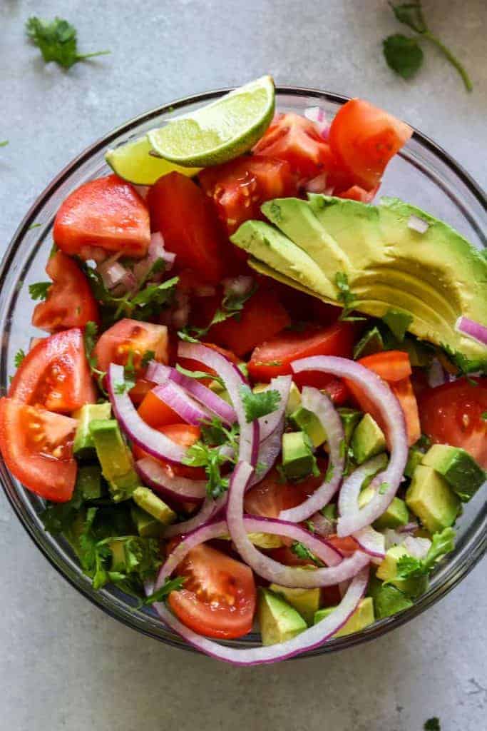 Avocado Tomato Cilantro Salad!  Refreshing and bursting with flavor this salad will be the perfect complement to any meal this summer!  Fresh tomato, avocado, cilantro all swimming in a lime dressing.  Plus top it with some crumbled queso fresco for a bit of creaminess.  