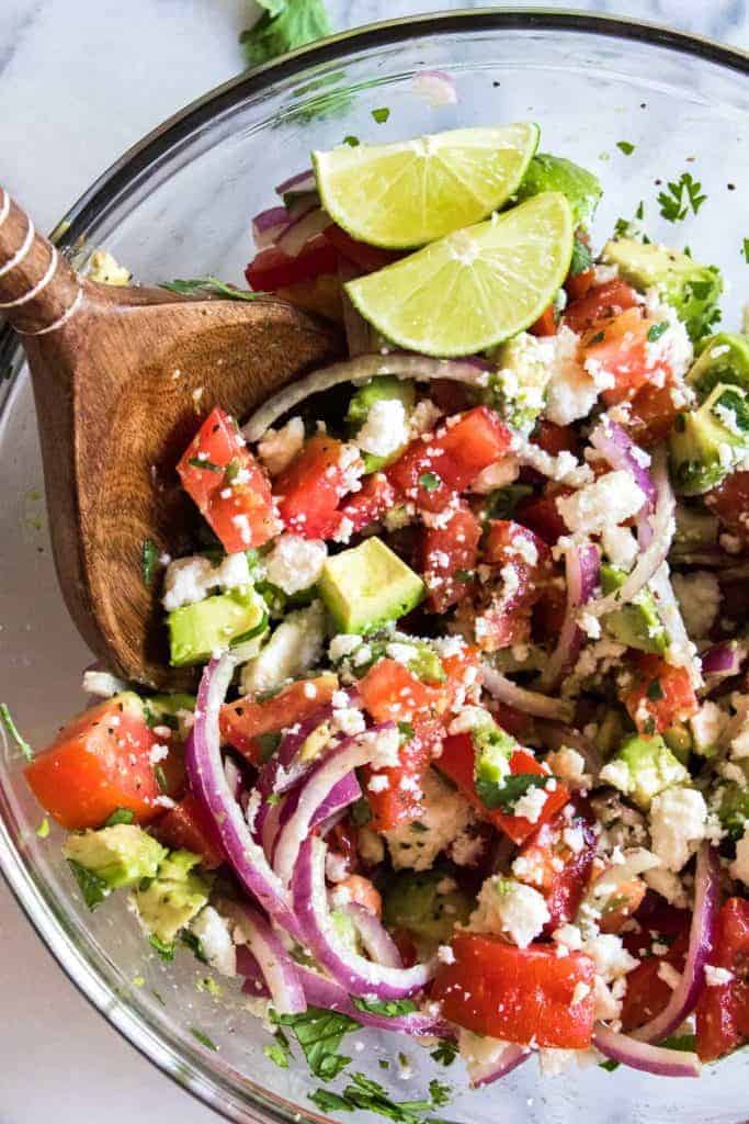 Avocado Tomato Cilantro Salad!  Refreshing and bursting with flavor this salad will be the perfect complement to any meal this summer!  Fresh tomato, avocado, cilantro all swimming in a lime dressing.  Plus top it with some crumbled queso fresco for a bit of creaminess.  