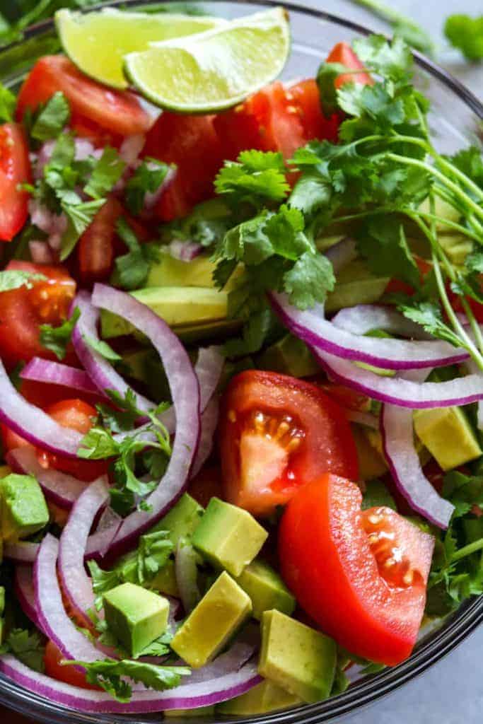 Avocado Tomato Cilantro Salad!  Refreshing and bursting with flavor this salad will be the perfect complement to any meal this summer!  Fresh tomato, avocado, cilantro all swimming in a lime dressing.  Plus top it with some crumbled queso fresco for a bit of creaminess.  