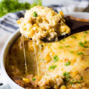 A spoon scooping out corn casserole, showing the cheese strings pulling away!