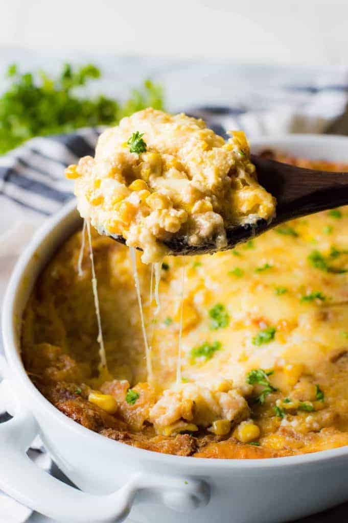 A spoon scooping out corn casserole, showing the cheese strings pulling away! 