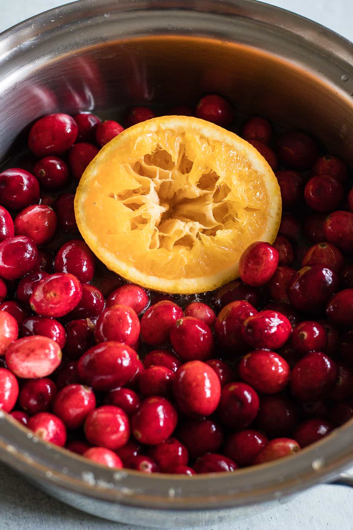 Fresh cranberries and orange peel in a small pot to make homemade cranberry sauce.