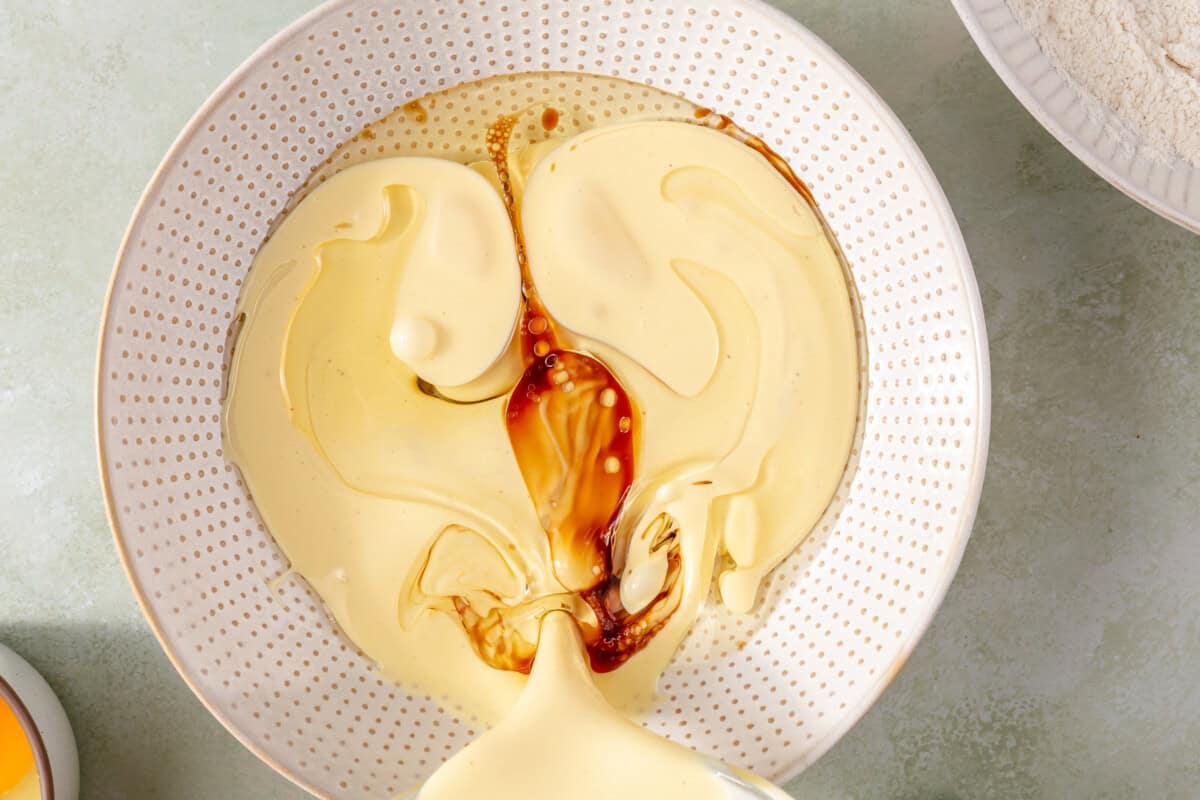 Combining wet ingredients for waffle batter in a mixing bowl. 