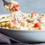 Fork digging into caprese mac and cheese with cheese stretching