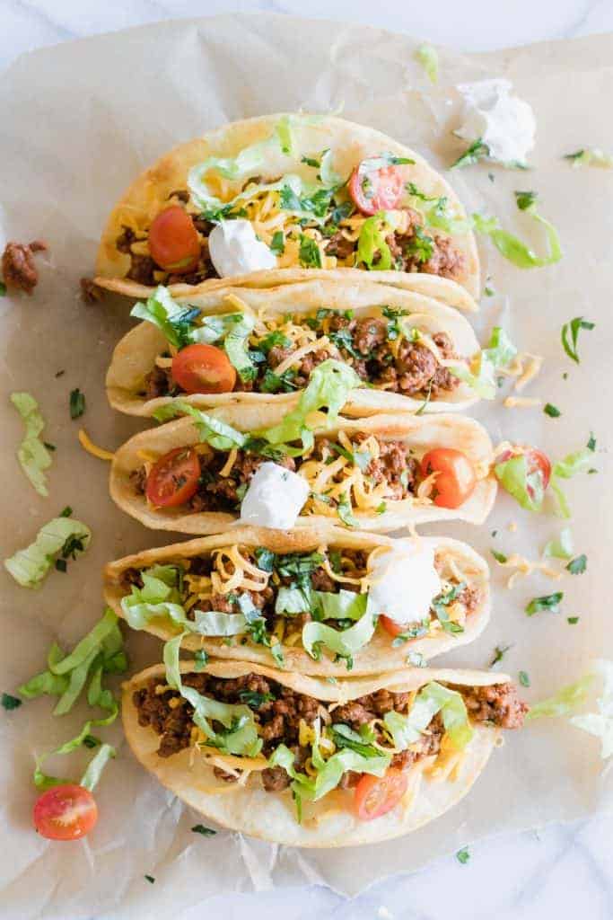 Classic ground beef tacos topped with cheese, lettuce, tomatoes.