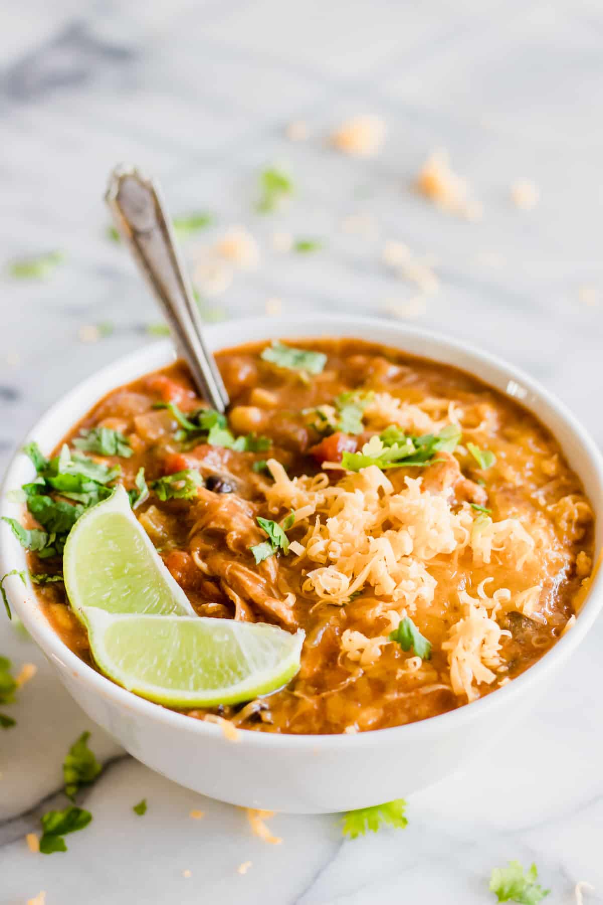 A spoon digging into a bowl of slow cooker chicken enchilada soup.
