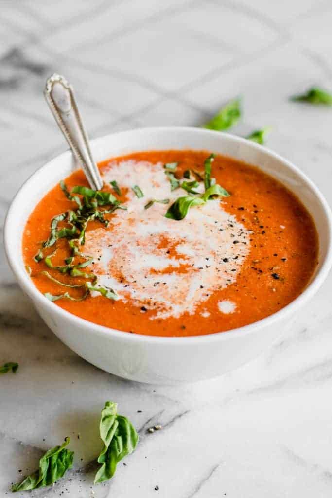 Bowl with a spoon dipped into roasted red pepper soup. 