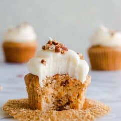 Moist and dense carrot cake cupcakes outside of the cupcake wrapper with a bite missing.