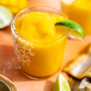 Frozen mango margarita served with a lime wedge.