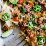 Sheet pan nachos topped with juicy ground beef, beans, cheese, jalapeño, tomato, sour cream and guacamole.