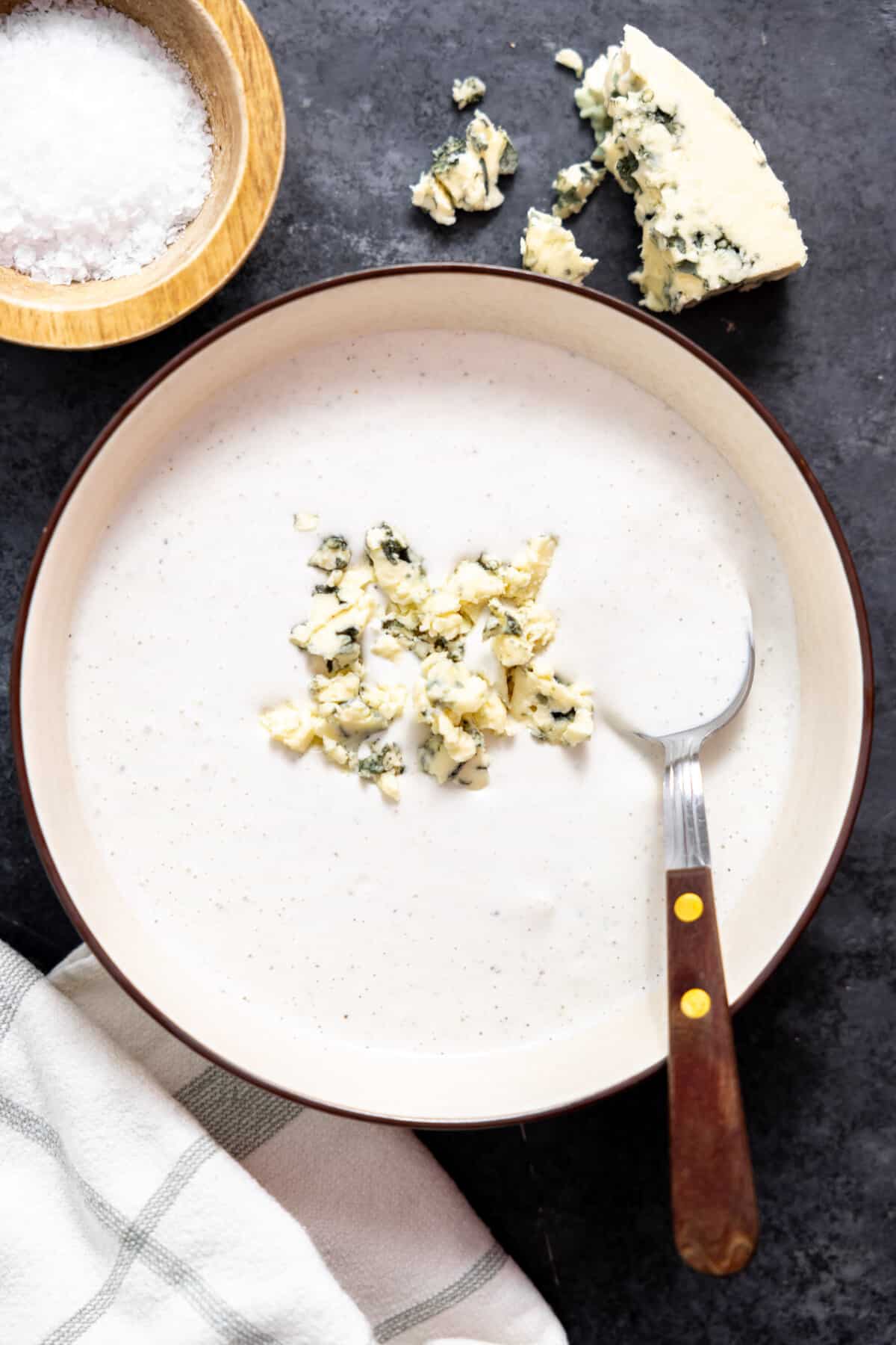 Blue cheese dressing in a bowl topped with crumbled cheese.