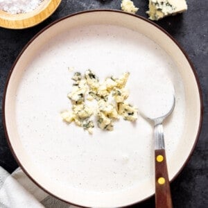 Blue cheese dressing in a bowl topped with crumbled cheese.