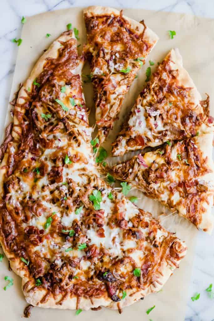 Pulled Pork Pizza. Pizza layered with BBQ sauce, cheese, pulled pork, bacon and red onion. Cut into slices.