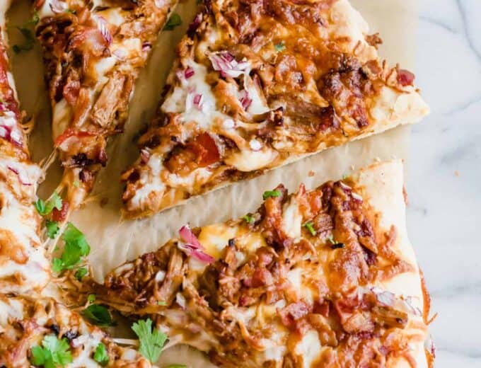 Pulled Pork Pizza. Pizza layered with BBQ sauce, cheese, pulled pork, bacon and red onion. Cut into slices.