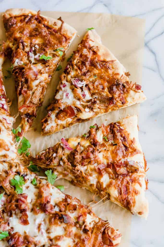 Pulled Pork Pizza. Pizza layered with BBQ sauce, cheese, pulled pork, bacon and red onion. Cut into slices. 