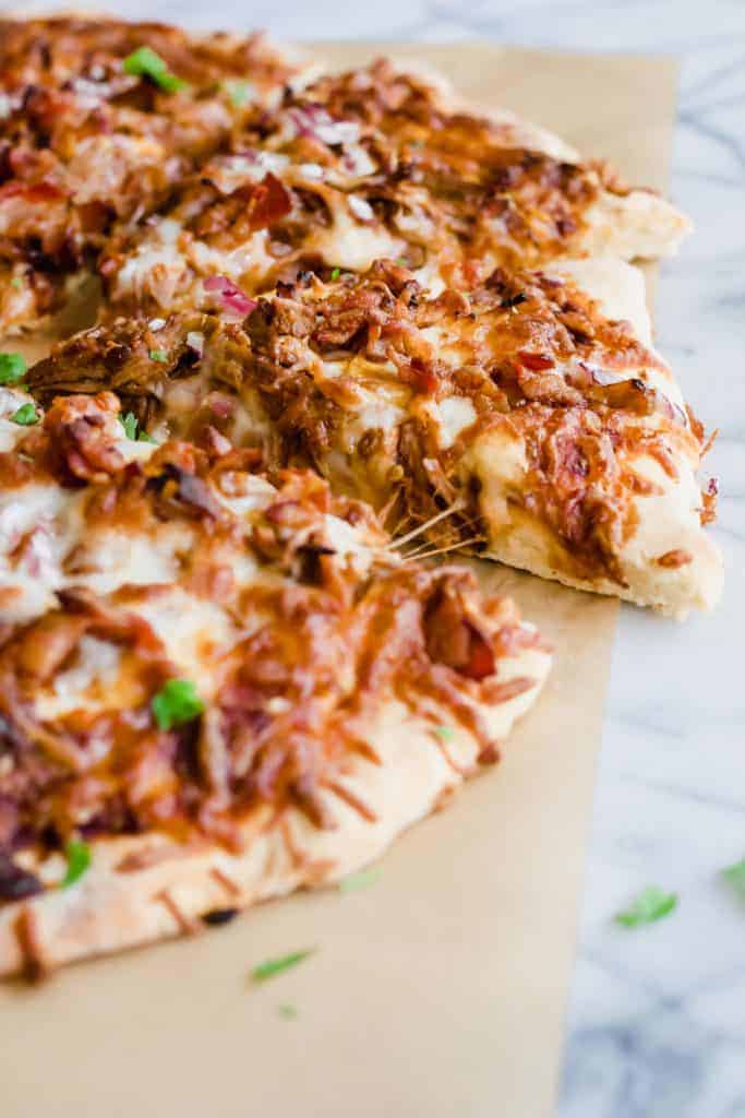 Pulled Pork Pizza. Pizza layered with BBQ sauce, cheese, pulled pork, bacon and red onion. Cut into slices.