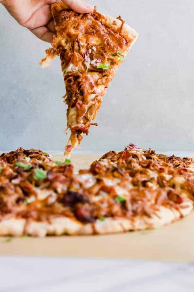 Pulled Pork Pizza. Pizza layered with BBQ sauce, cheese, pulled pork, bacon and red onion. Cut into slices.