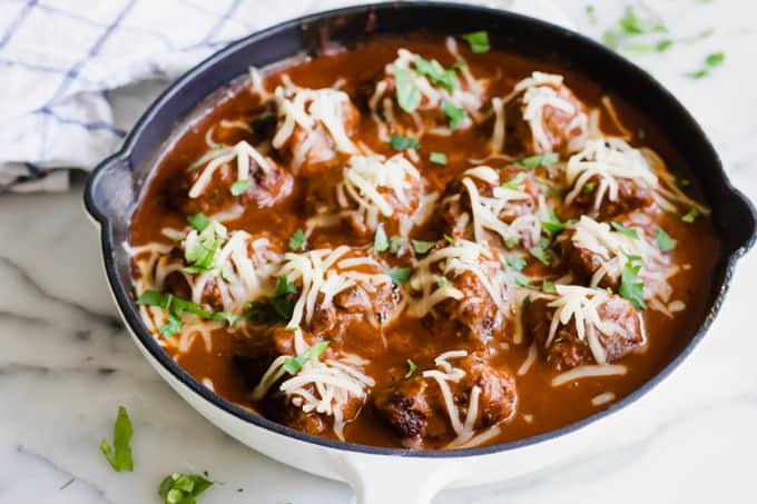 Tex Mex Enchilada Meatballs in a skillet topped with cheese.