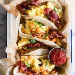 Breakfast tacos loaded up with breakfast potatoes, scrambled egg, bacon and topped with cilantro.