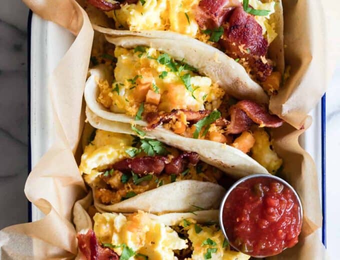 Breakfast tacos loaded up with breakfast potatoes, scrambled egg, bacon and topped with cilantro.