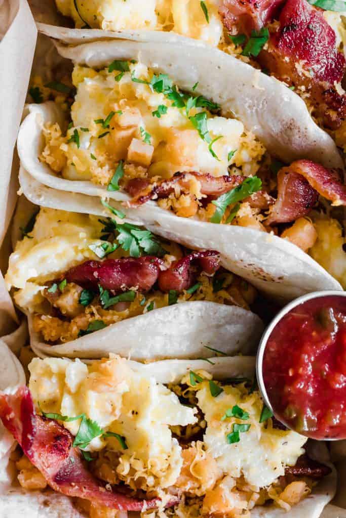 Close up of flour breakfast tacos with egg, bacon, and potatoes.