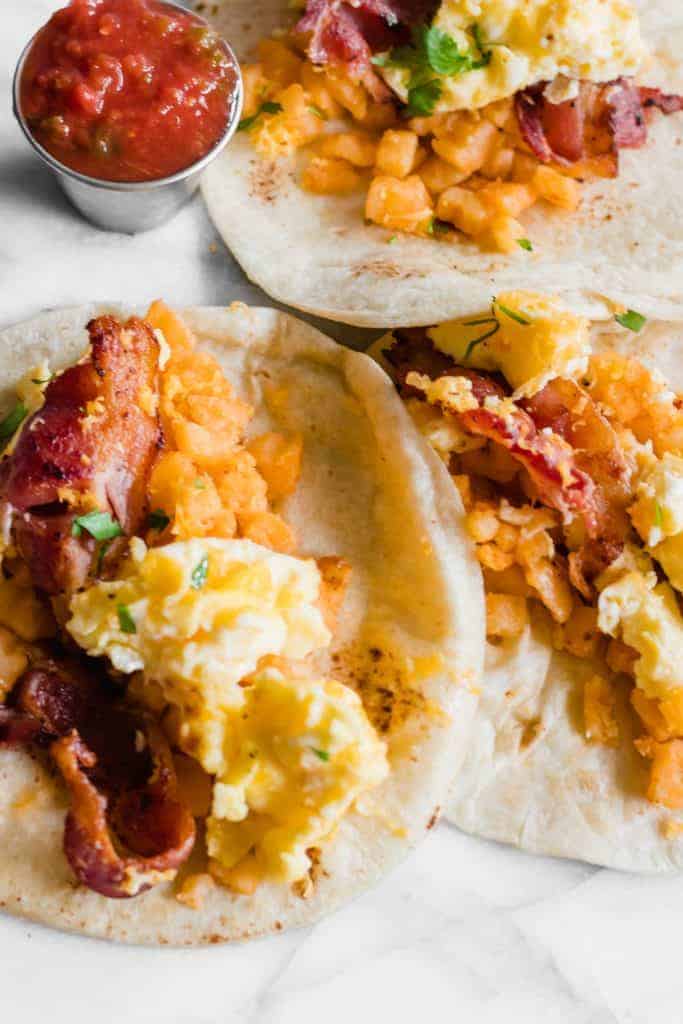 Texas Style Breakfast Tacos opened, showing eggs, bacon and potatoes.