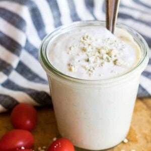 Jar of smooth blue cheese dressing topped with blue cheese crumbles.