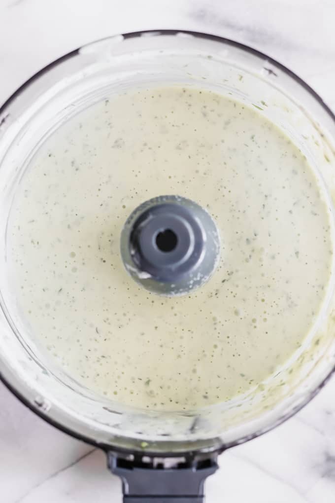 A food processor filled with smooth and creamy avocado ranch dressing.
