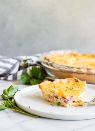 A ham and cheddar quiche served on a plate.