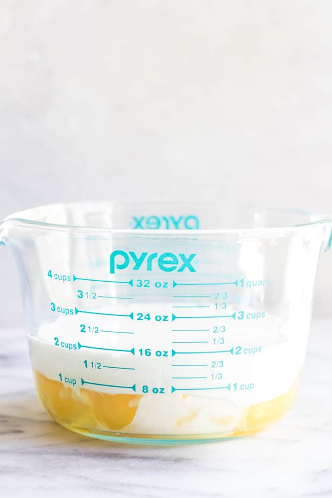 Large measuring cup filled with eggs and cream for eggs Benedict quiche. 