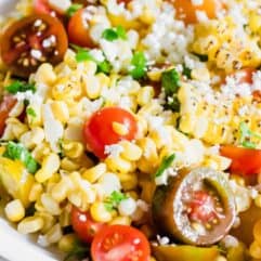 Close up of roasted corn, tomatoes, cilantro, and queso fresco in a roasted corn salad.