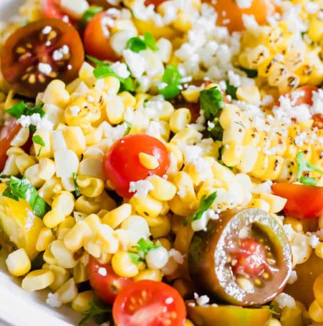 Close up of roasted corn, tomatoes, cilantro, and queso fresco in a roasted corn salad.