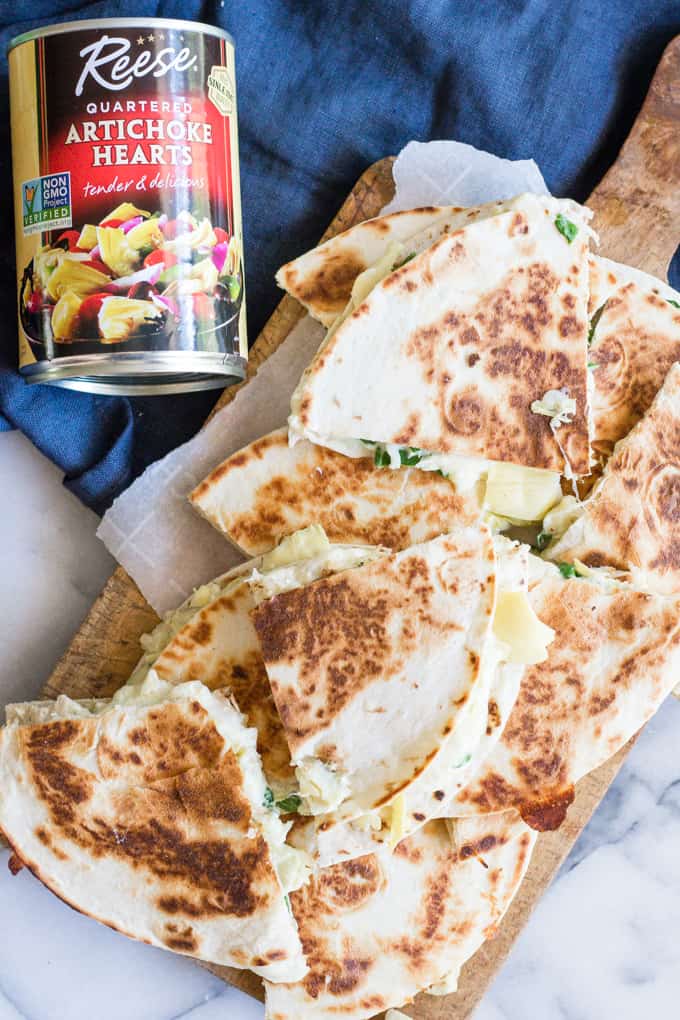 Overhead image of a tray of spinach and artichoke chicken quesadillas with a can of Reese Quartered Artichoke hearts.