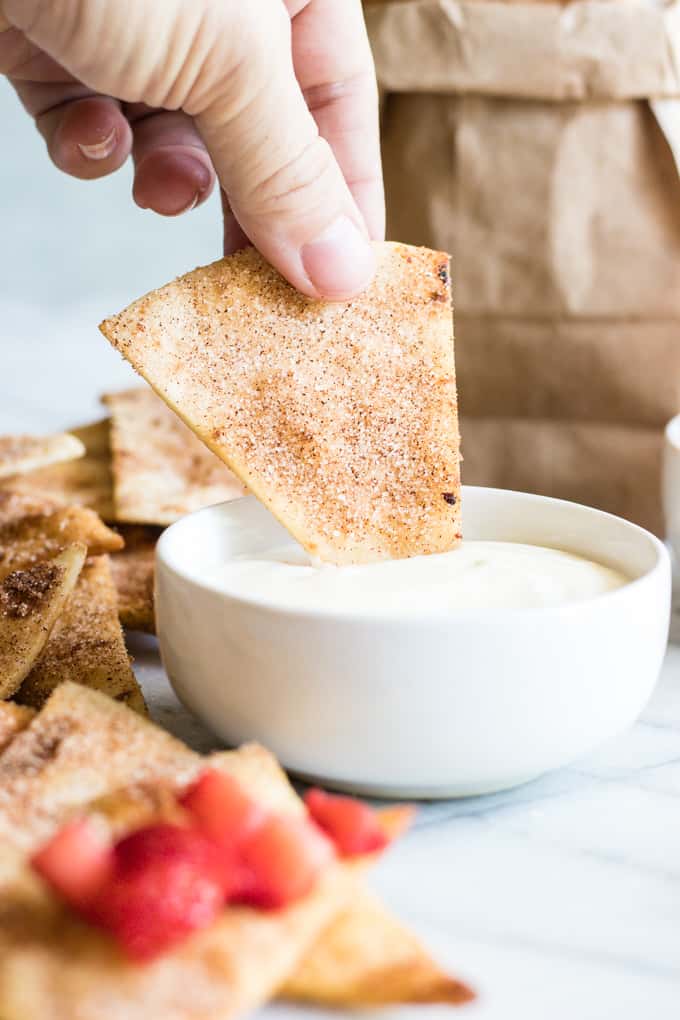 Cinnamon Tortilla Chips dipping into a cream cheese glaze.