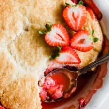 Spoon scooping out strawberry cobbler.