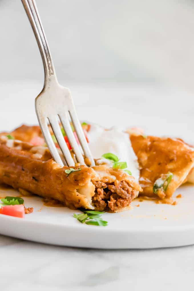 Chorizo Enchiladas on a plate with a fork digging in. 