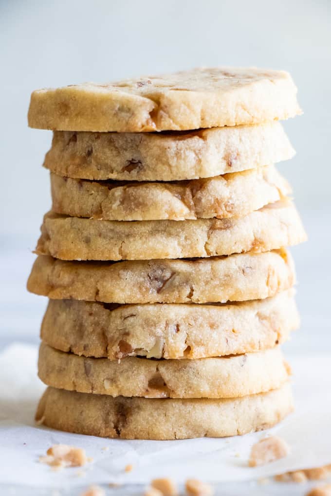 Large stack of butter pecan shortbread cookies, loaded with bits of chopped pecans and toffee bits.