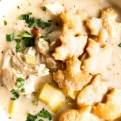 Bowl filled with creamy chicken pot pie soup and topped with pie crust crackers that are shaped like leaves.