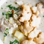 Close up view of chicken pot pie soup, topped with fresh parsley and pie crust crackers.
