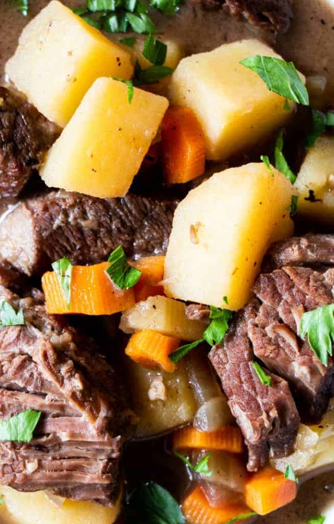 Close up view of chunks of tender meat, chunks of potato, pieces of carrot, all in a classic beef stew.