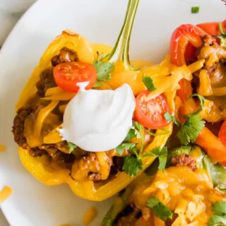 Halved yellow bell pepper filled with ground beef taco meat, cheese, sour cream and tomatoes.