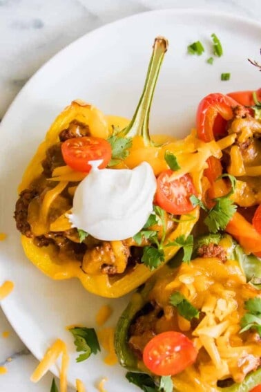 Halved yellow bell pepper filled with ground beef taco meat, cheese, sour cream and tomatoes.