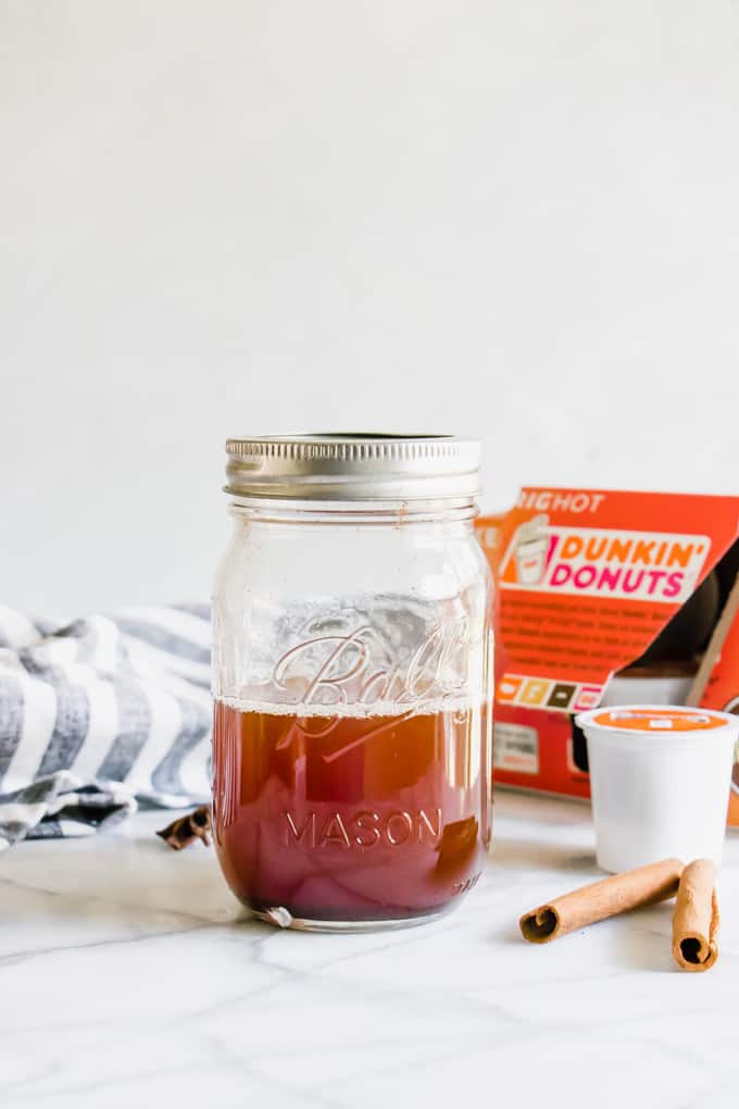 A glass jar holding apple spice syrup for making homemade lattes.