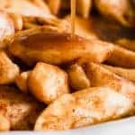 Tender baked apple slices with sauce being drizzled over top.