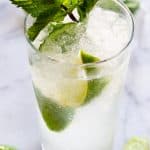 Classic mojito garnished with lime wedges and mint leaves.